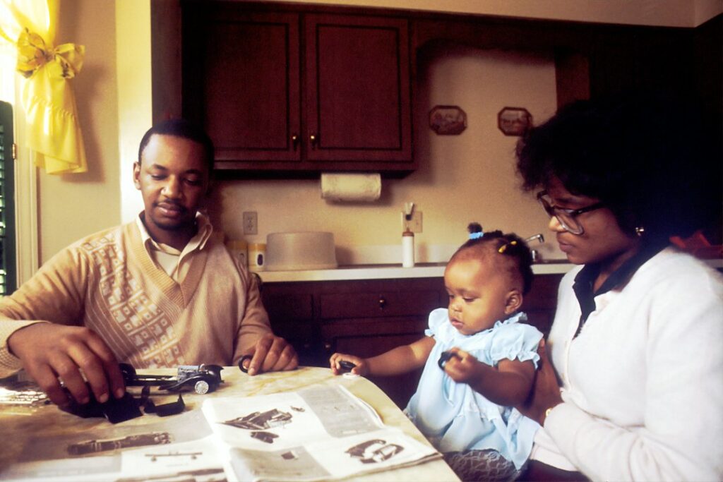 A couple reviews insurance documents beside a laptop, home inventory folder, and vehicle keys.