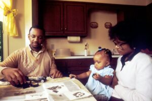 A couple reviews insurance documents beside a laptop, home inventory folder, and vehicle keys.